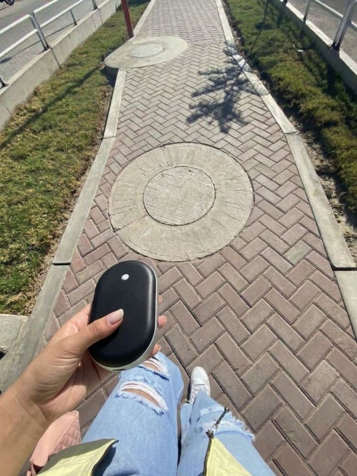 Mano sujetando el calentador de manos Calore durante un paseo por la calle
