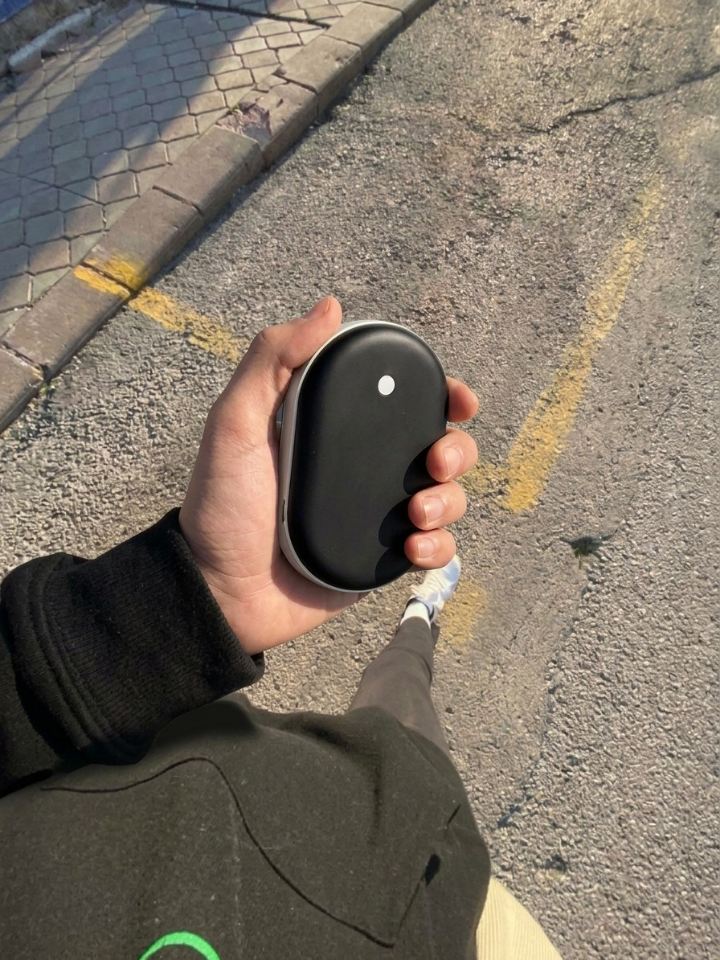 Mano sujetando el calentador de manos Calore al aire libre con luz de sol