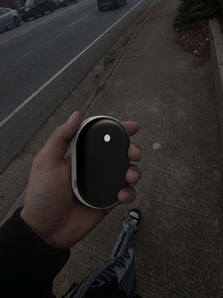 Mano sujetando el calentador de manos Calore caminando por la calle