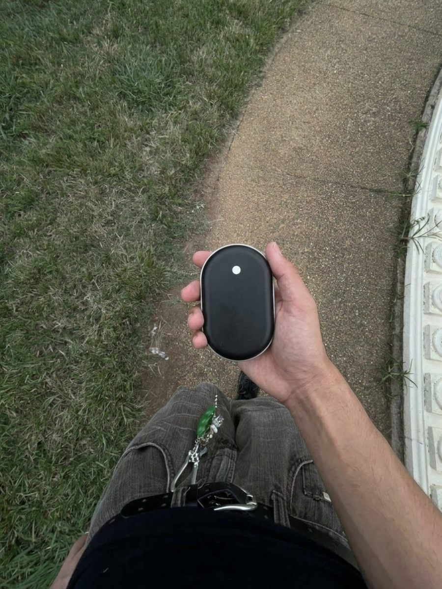 Mano sujetando el calentador de manos Calore durante un paseo por el parque