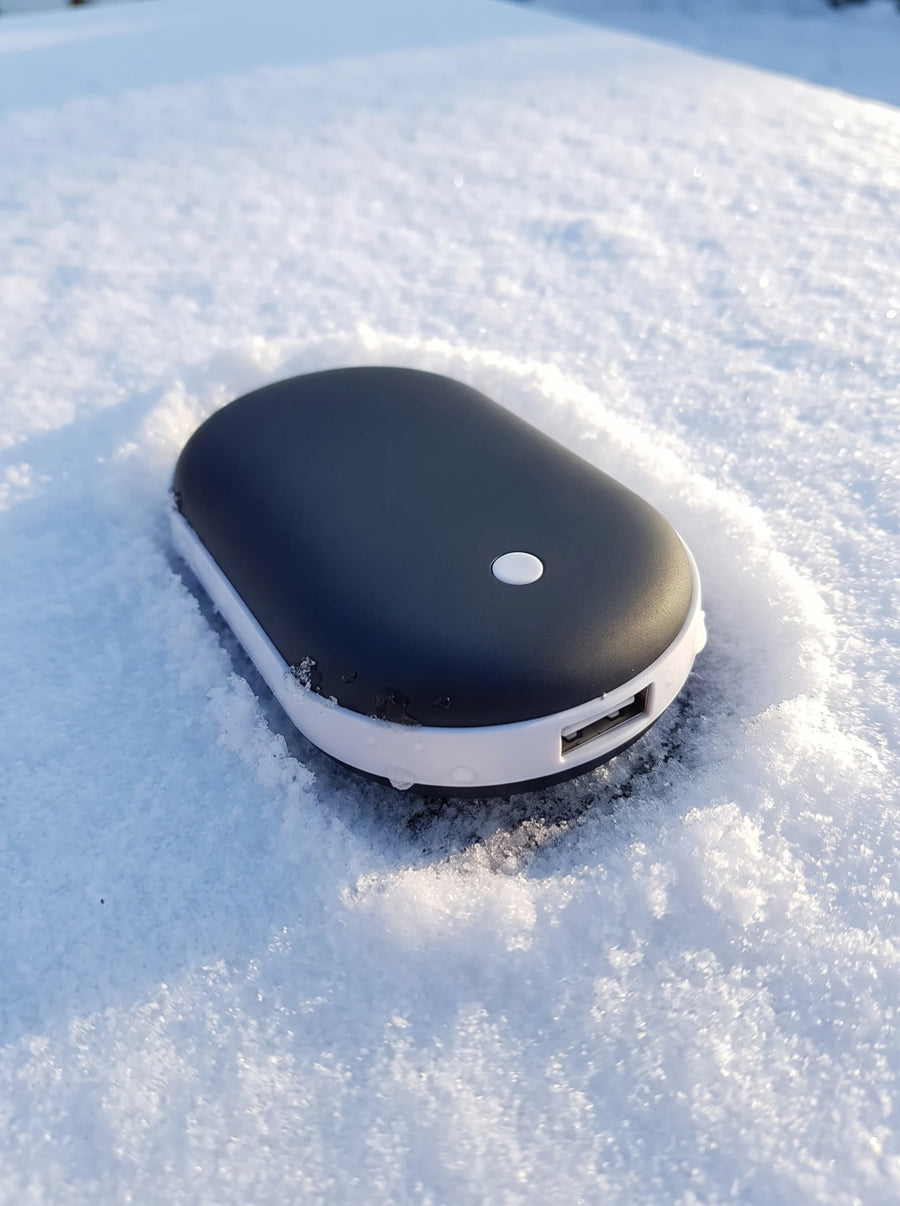 Calentador de manos Calore sobre la nieve con la luz del sol