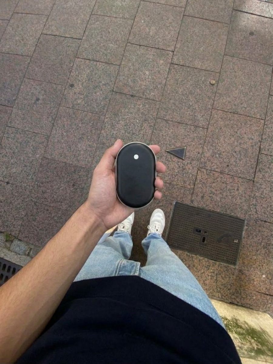 Mano sujetando el calentador de manos Calore mientras se camina por la ciudad